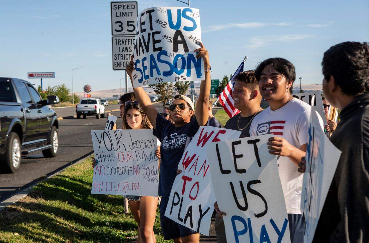Members of the Chiawana High School football team waved signs at passing cars during an Open Our Schools Rally held in Pasco.