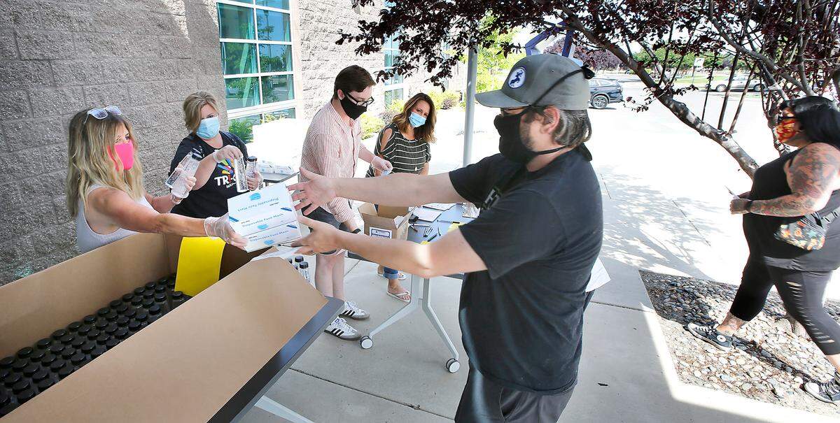 Ryan Wattenbarger of Moonshot Brewing in Kennewick collects face masks and hand sanitizer from Michelle Chunn of Visit Tri-Cities at the Tri-Cities Open and Safe Coalition’s free distribution of protective equipment for small businesses.