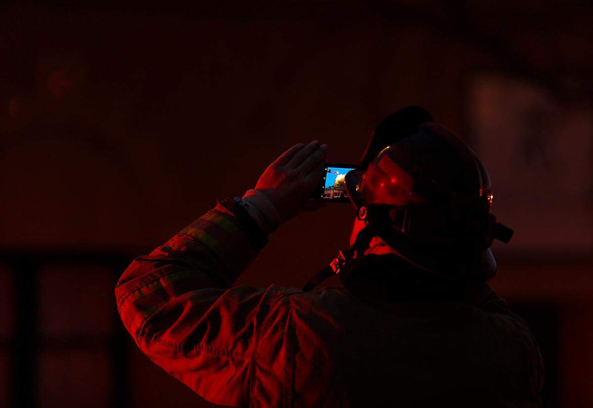 Emergency lights from a fire truck illuminate a firefighter photographing the scene of Friday’s early morning blaze in downtown Kennewick.