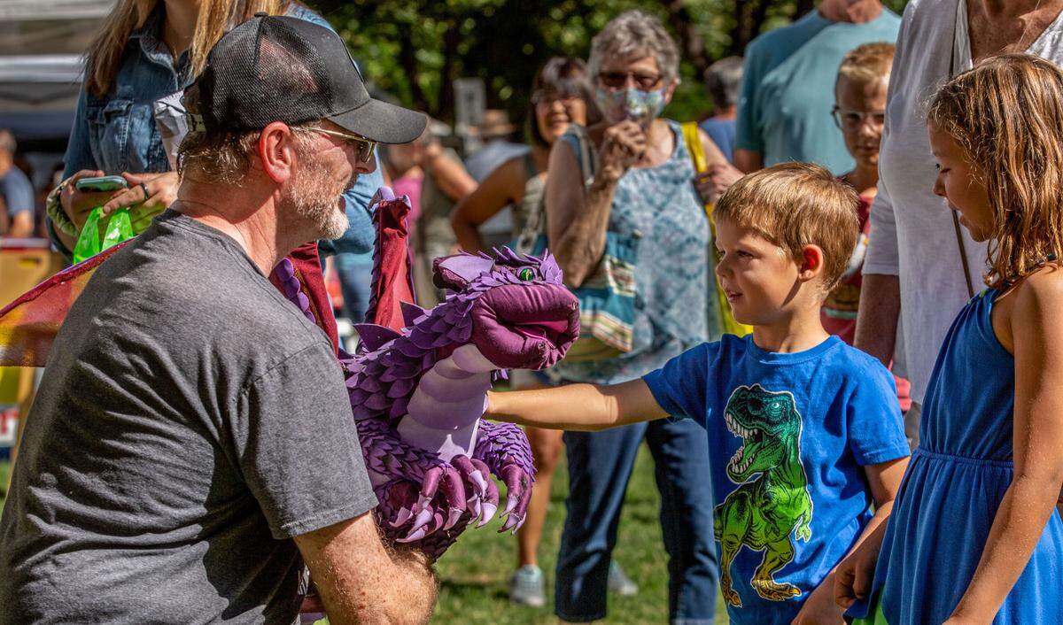 Beau Manley, 4, of West Richland, pets Henry, a purple dragon created by artist Herb Leonhard of Prosser during the first day of the 70th annual Art in the Park event at Howard Amon Park in Richland. The event, which runs Friday and Saturday, features over 300 local and national artists, as well as food vendors and entertainers. Leonhard’s illustrative work is featured in a number of children’s books, coloring books and in large murals at Adventures Underground in the Uptown in Richland.