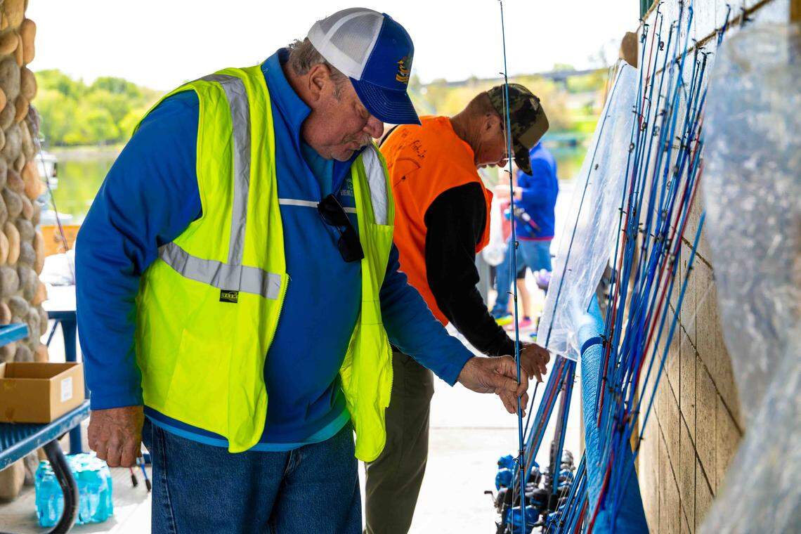 Ken Hagn, left, and Larry Larson, volunteers with Kids Outdoor Education, organize fishing rods for distribution during Kids Fishing Day at Columbia Park Pond in Kennewick. The group provides rods, reels, and shirts for participating children.