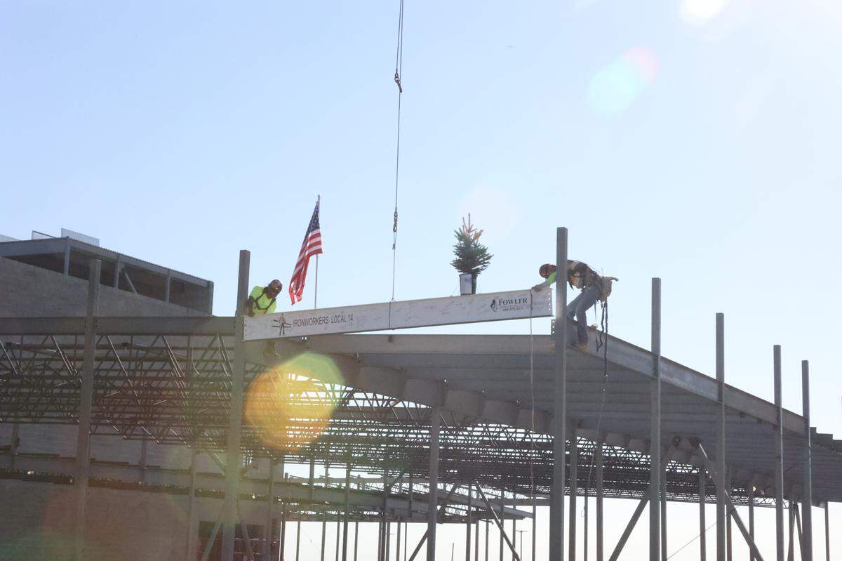 Construction workers install the final structural beam at Sageview High School.