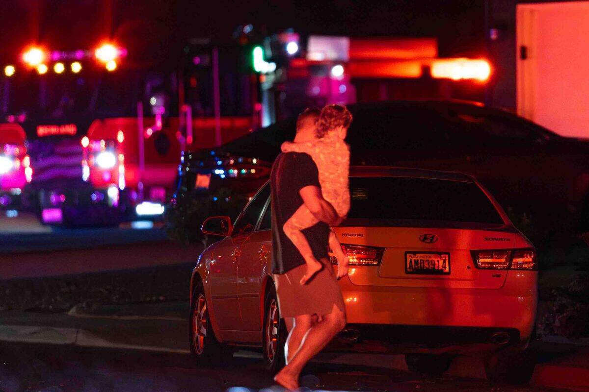 A father carries his child away from the area after nearby homes were evacuated during an early morning residential fire in the 5200 block of Jacksnipe Court on Sunday in West Richland.