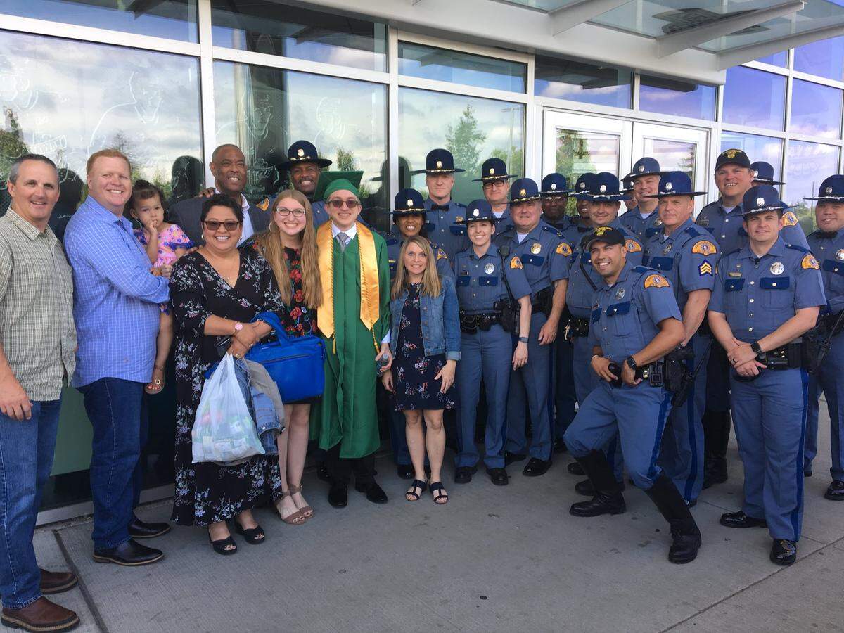 Jim Saunders, in the cap and gown, with his mother, sister and extended Washington State Patrol family at his high school graduation.