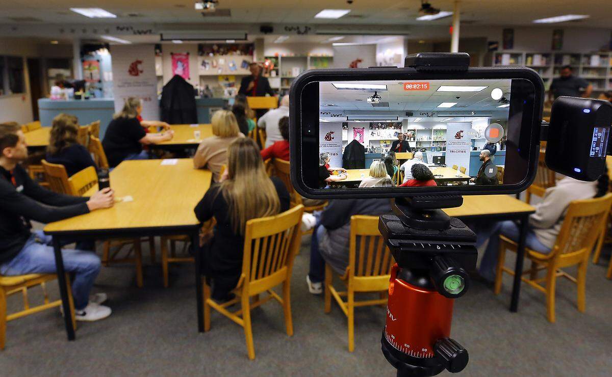A cellphone camera records John Mancinelli, WSU Tri-Cities Academic Director for the College of Education, Sport and Human Sciences, as he conducts Thursday morning's ceremony in the Park Middle School library designating the Kennewick school a WSU Tri-Cities College of Education, Sport and Human Services Teaching Laboratory School. 