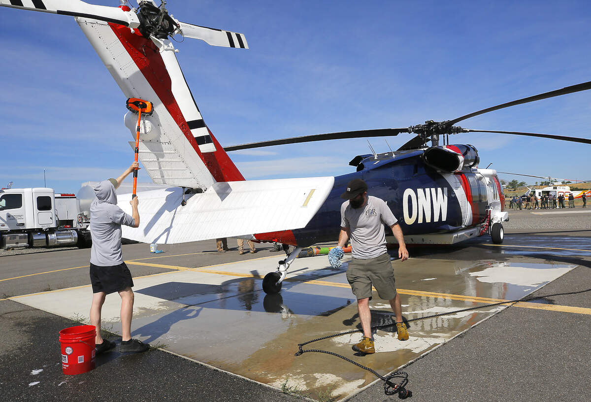 Mechanics Lance Harvey, left, and Matthew Hygh, wash a firefighting Black Hawks from Northwest Helicopters on the tarmac at the Port of Benton's Richland Airport. The helicopter are being used to battle wildfires around Tri-Cities.