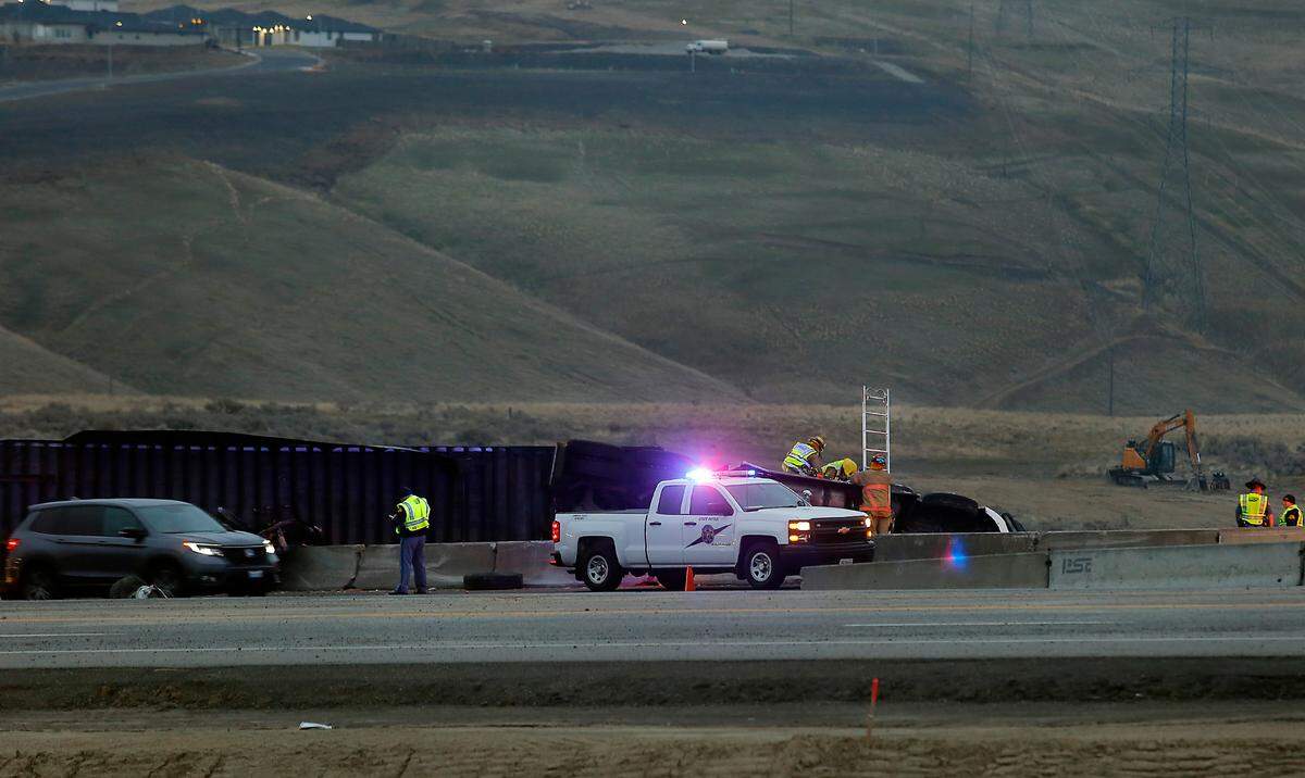 Rescue workers use a ladder to gain access into the cab of overturned semi-truck in the northbound lane of Highway 395 at Ridgeline Drive early Thursday morning in Kennewick.