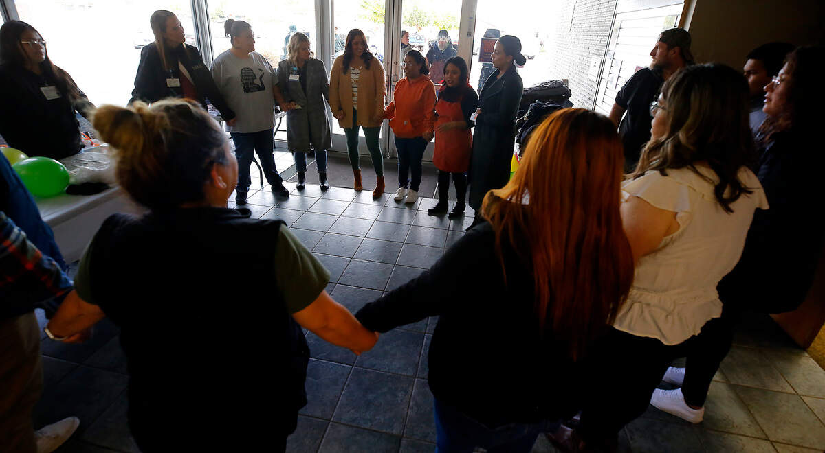 Volunteers and community leaders hold hands while speaking words of gratitude just prior to opening the doors on the first anniversary of the Homeroom Connect community resource program at the Pasco branch of the Mid-Columbia Libraries.