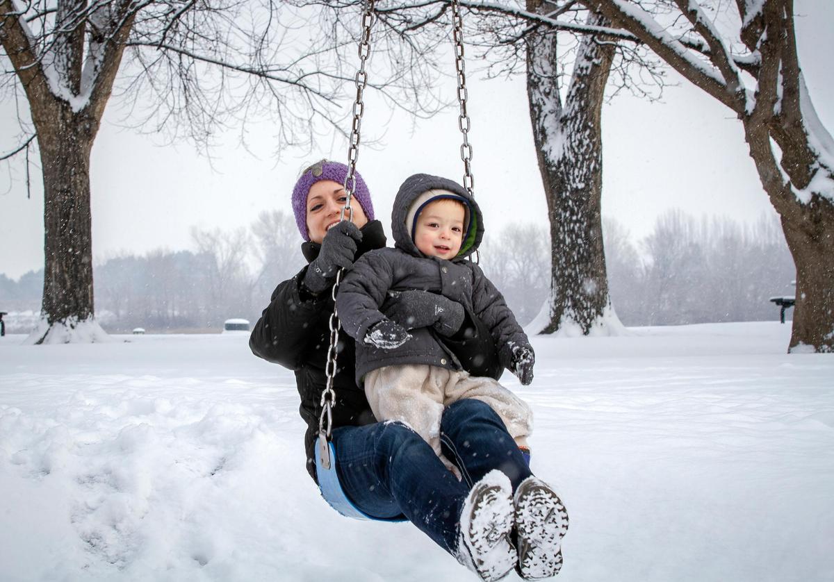 Emily Choi holds her 2-year-old son, Paxton, as they ride on the zip line swing in Howard Amon Park in Richland on Friday. They were headed to a music lesson but the class was canceled by the weather.