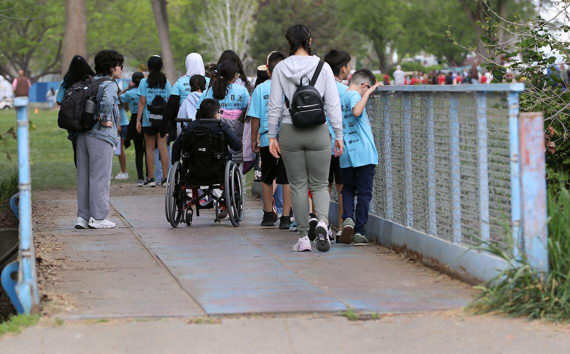 Elementary students, teacher and parent chaperones cross a small foot bridge after releasing the salmon fry they raised in their classroom.
