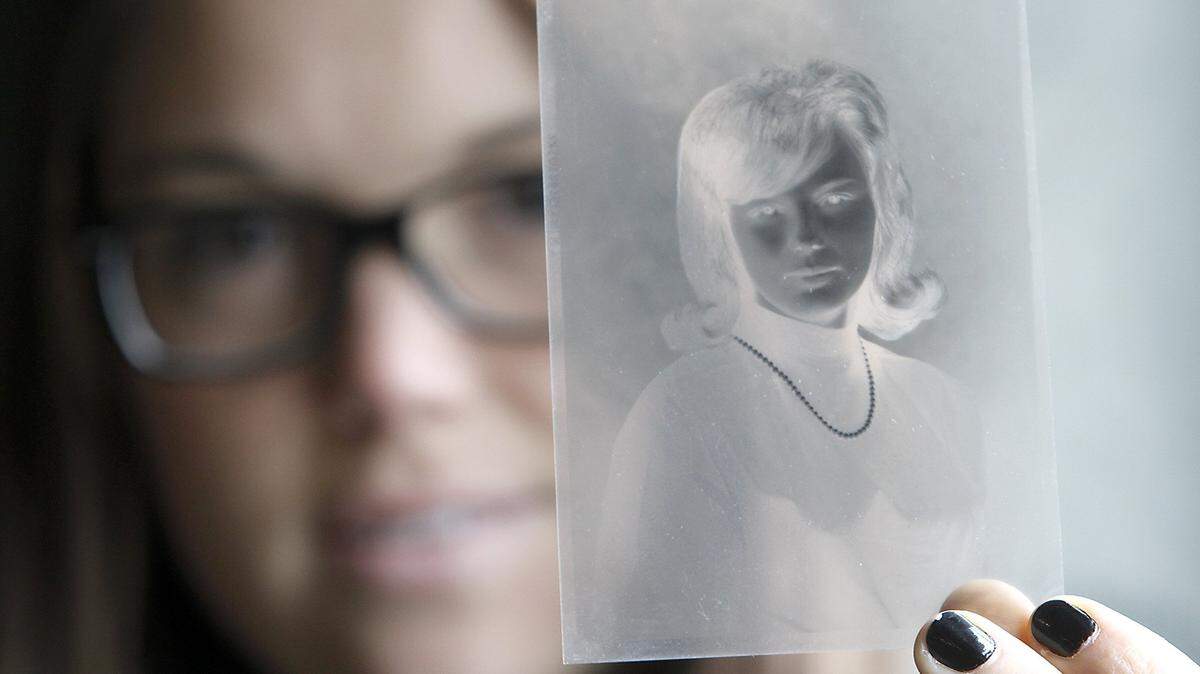 A Reach center employee in 2014 holds up a black and white negative from a local photographer taken for a senior high school portrait in 1964.