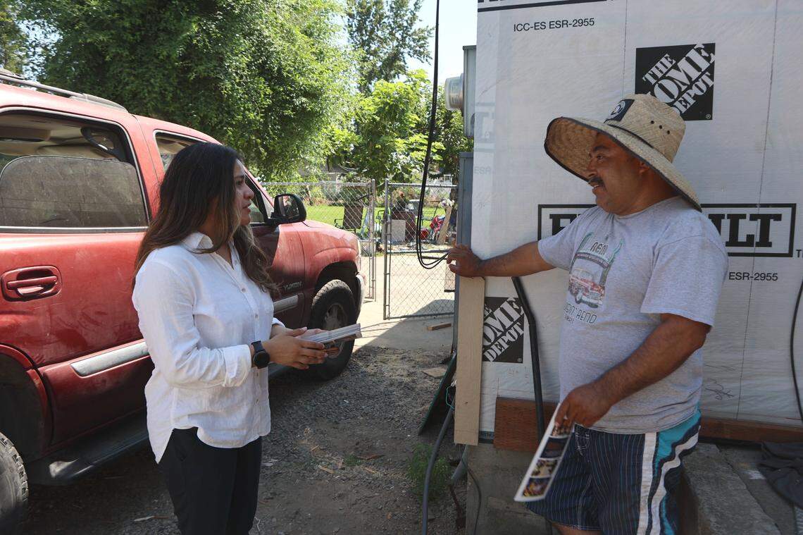 Democrat Senate candidate Maria Beltran speaks with a farmworker outside his home in Toppenish.