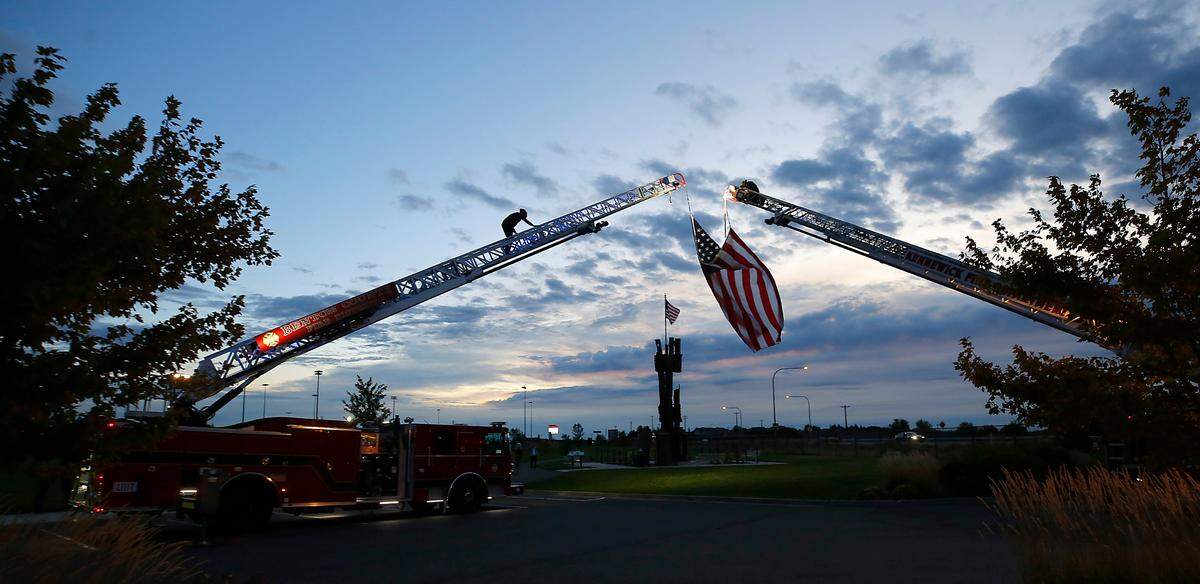 Firefighters from the Kennewick Fire Department and Benton County Fire District 1 suspend a U.S. Flag between two ladder trucks for the 23rd anniversary of the September 11, 2001 terrorist attacks.