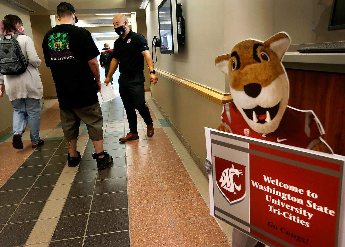 WSU-Tri-Cities students arriving for the first day of class Monday are greeted by Jason Li, assistant director of admissions, and a cutout of the Cougar mascot, Butch, at the Richland campus. It’s the first time the Richland campus held in-person classes since 2020.