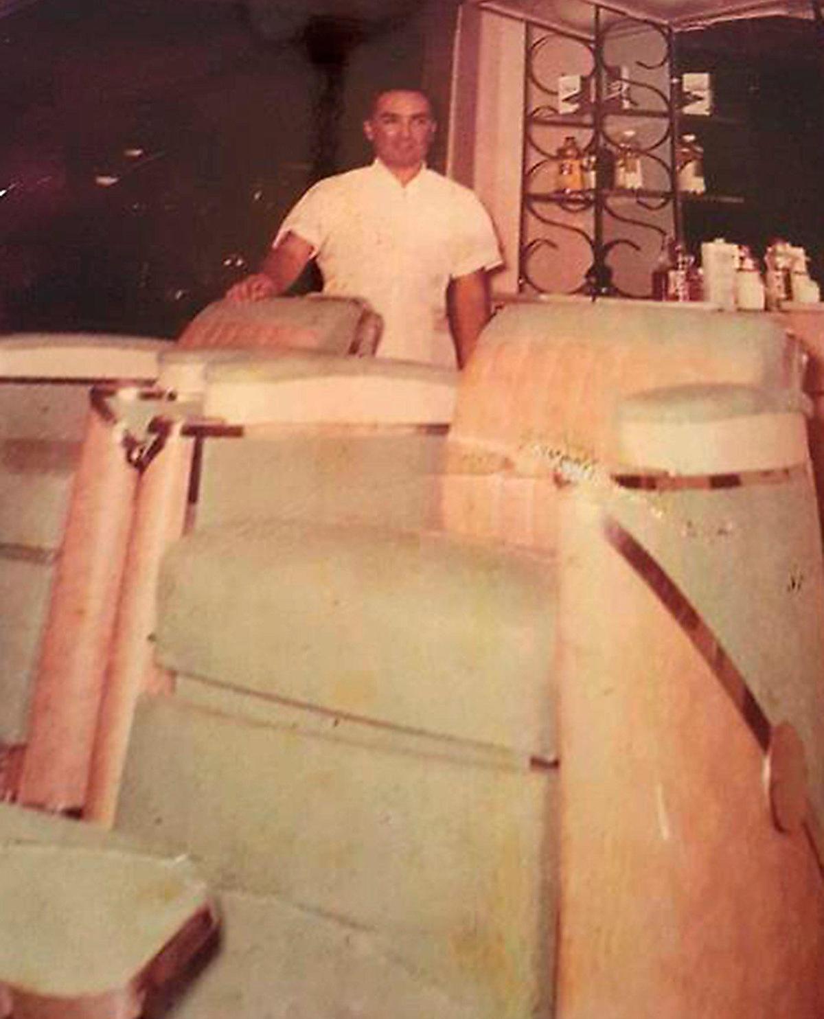 Barber Larry Maltos poses for a photo with turquoise barber chairs that were placed at the front when the shop first opened. The chairs were classically built for comfort and the total experience of a scalp massage, shave and a custom haircut. Maltos later expanded the shop by pushing the front wall out about 6 feet.