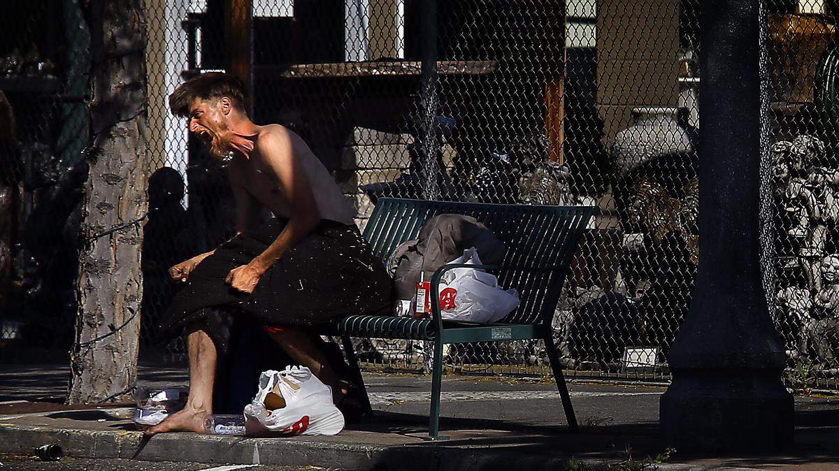 A highly-agitated partially-clothed man sits on a bench early Tuesday on West Kennewick Avenue in the downtown Kennewick business district. New prohibitions on sitting and lying in downtown Kennewick were passed this week by the Kennewick City Council.