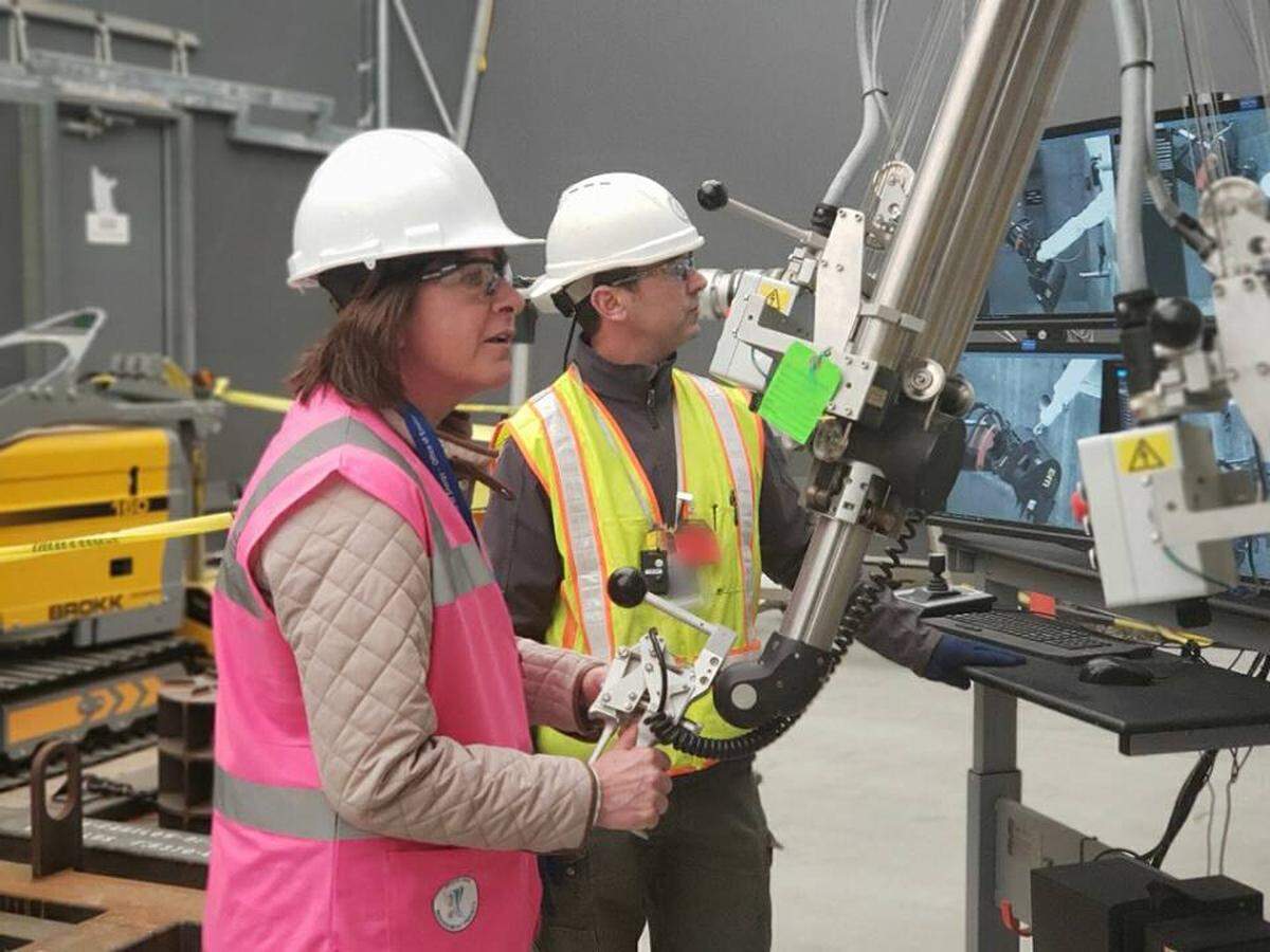Anne White, Department of Energy assistant secretary for environmental management, takes a hands-on approach at the 324 Building mock-up during her tour of Hanford. Workers at the mock-up are testing equipment that will remotely remove highly radioactive soil from a spill beneath the actual 324 Building.