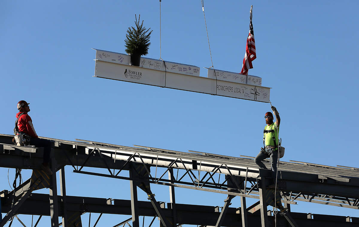 Ironworkers Colton Williams, left, and Cole Sellers install the final steel beam for the Orion High School project during Thursday morning’s topping off ceremony.