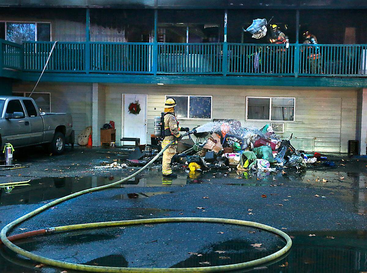 Kennewick firefighters remove charred and smoldering belongings from a fire damaged top floor apartment Thursday morning from at the 16-unit Breezeway Apartments complex on West Bruneau Place in Kennewick. Fire officials say no one was injured in the early-morning fire.