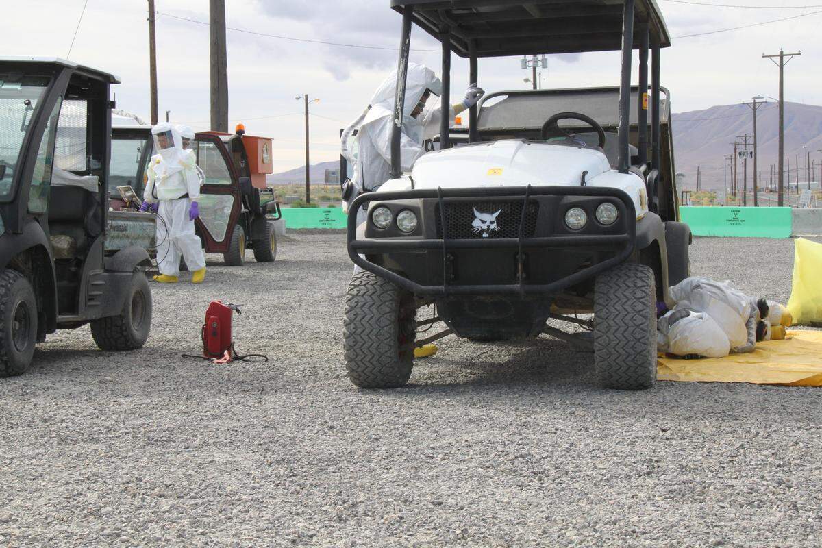 Workers wearing respirators and protective clothing perform maintenance on equipment that will be used to support demolition as it restarts at the Hanford nuclear reservation’s Plutonium Finishing Plant.