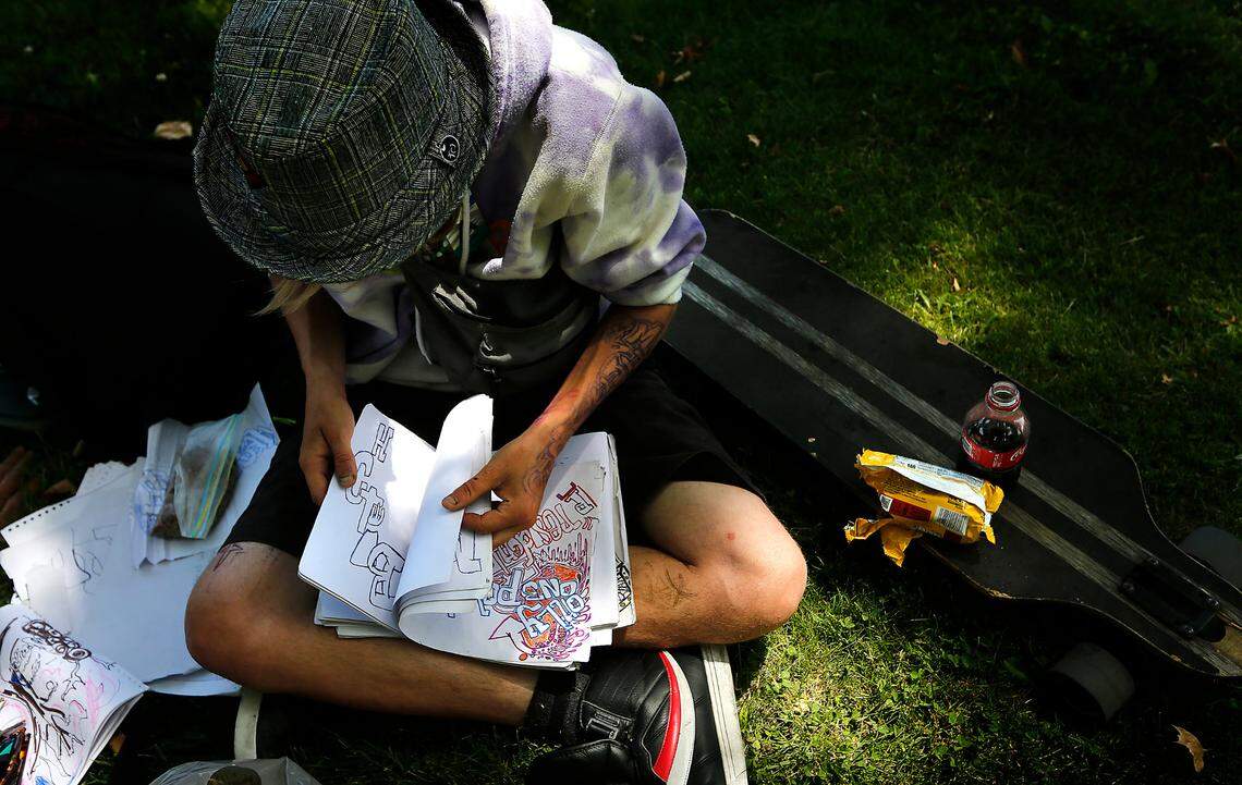 Stevo Wold leafs through his drawings while explaining the meaning of the colors, symbols and lettering he’s incorporated into the artwork. Wold, 29, says he’s been living on the streets since he was 16 years-old.