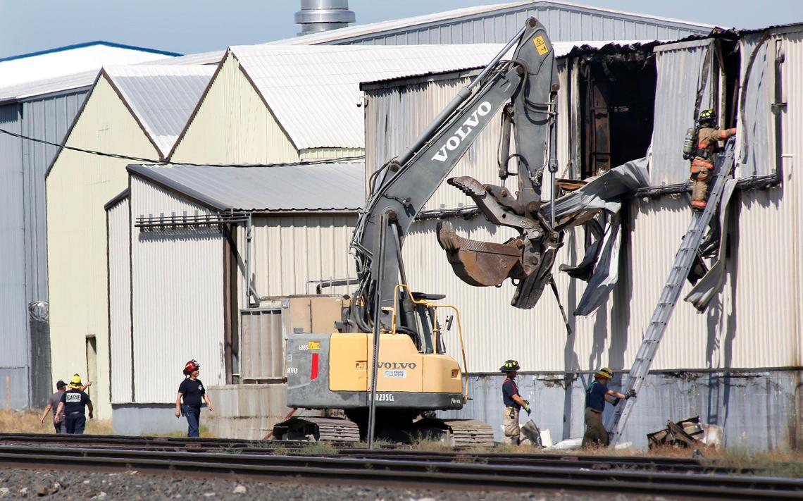 Kennewick fire invistigators use an excavator to tear open the sides of the Baker Produce building Wednesday afternoon following a fire that heavily damaged the food processing facility. Watch a video at: tricityherald.com/video