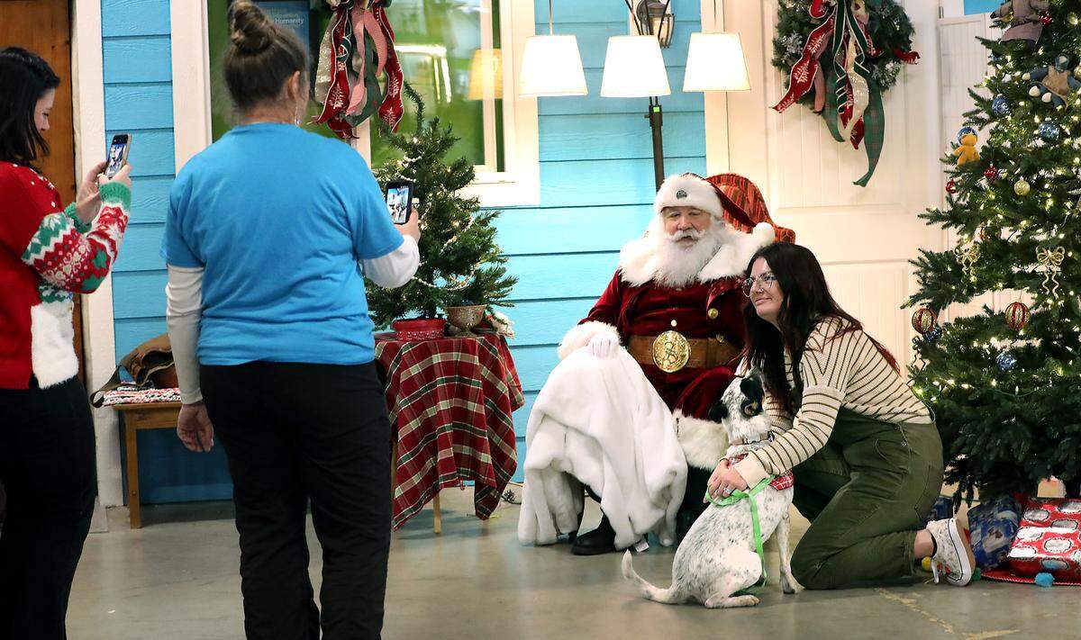 Jennifer Turner and her newly adopted healer mix named Gwen pose for a photo with Santa Claus. Taking photos are, from left: Erica Taylor, Tri-County Partners Habitat for Humanity community outreach and engagement coordinator, and Becky Kettle-Gay, board member with Pronto Puppy Rescue.