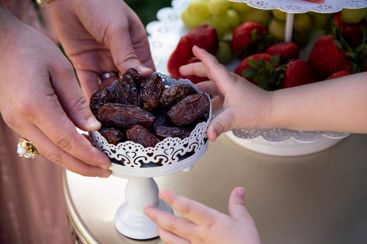 Abdullah reaches for a dish of dates as his mother, Somayyah, places them on the table. In the evening, the family usually breaks fast with dates, fruit and water.