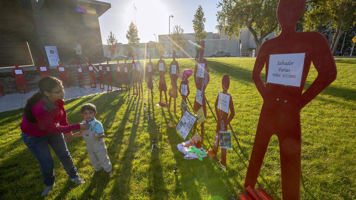 Maria Marin with her son Jeremiah Moran looks at a red, life-size silhouette at John Dam Plaza in Richland on Thursday during the annual Domestic Violence Vigil held by Domestic Violence Services of Benton and Franklin Counties.