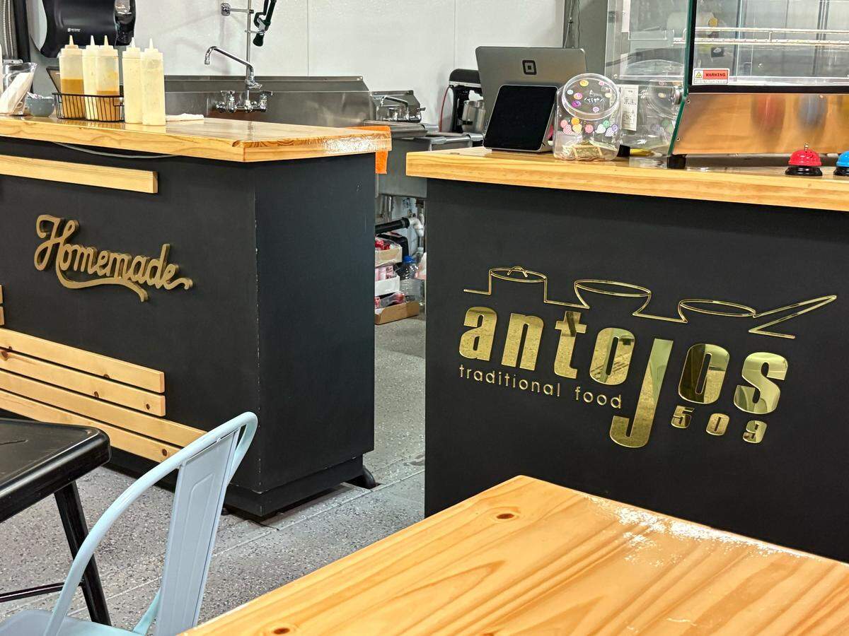 The pay counter at Antojos 509 shows the Venezuelan food spot’s branding in shiny gold.