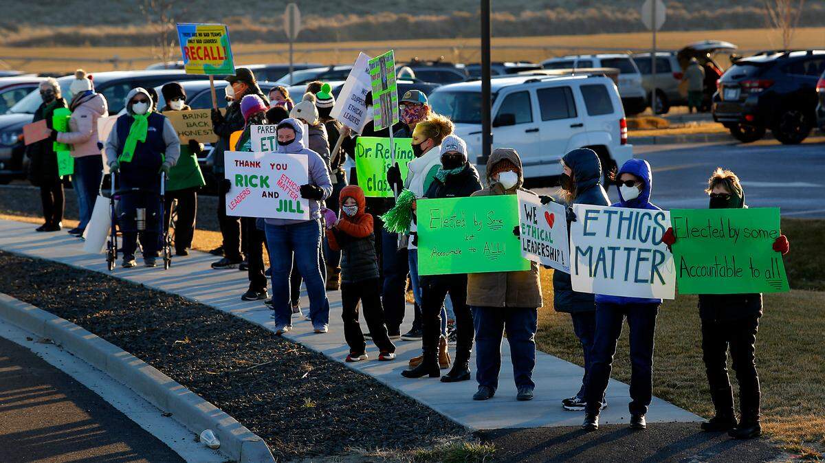 About 50 people hold signs Tuesday afternoon during a rally organized by the Community for an Ethical School Board outside of the Richland School District administration off Keene Road in West Richland.