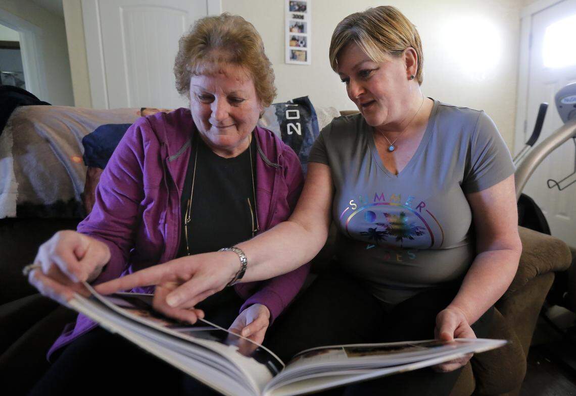 Wanda McCollom, left, and her daughter Heather Escobar sit inside of their home looking at photos of two of their family members, John and Amy McCollom, that they lost to suicide.