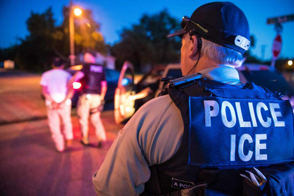 Immigration and Customs Enforcement officers detaining a man.
