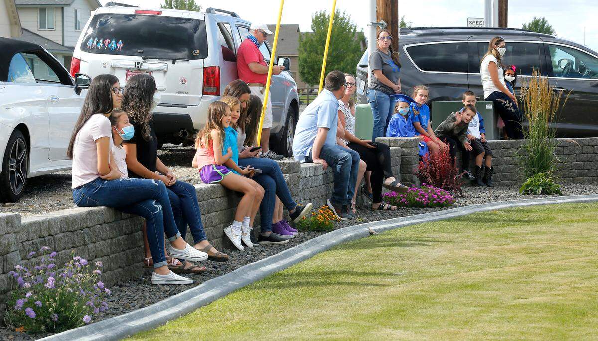 Kindergarten graduates and their family members keep socially distanced in the front yard of teacher Andrea Patterson’s West Richland home during a “porch walk” graduation for students in her White Bluffs Elementary class. Some parents requested the chance to close out the school year with the coronavirus modified celebration. Students also collected a certificate and a scrapbook containing papers and drawings from their first year of school.