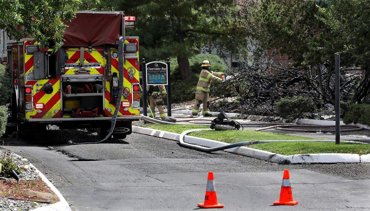 Kennewick firefighters cut apart charred shrubs on Thursday July 3, after extinguishing them in the 5200 block of West Clearwater Avenue in Kennewick.