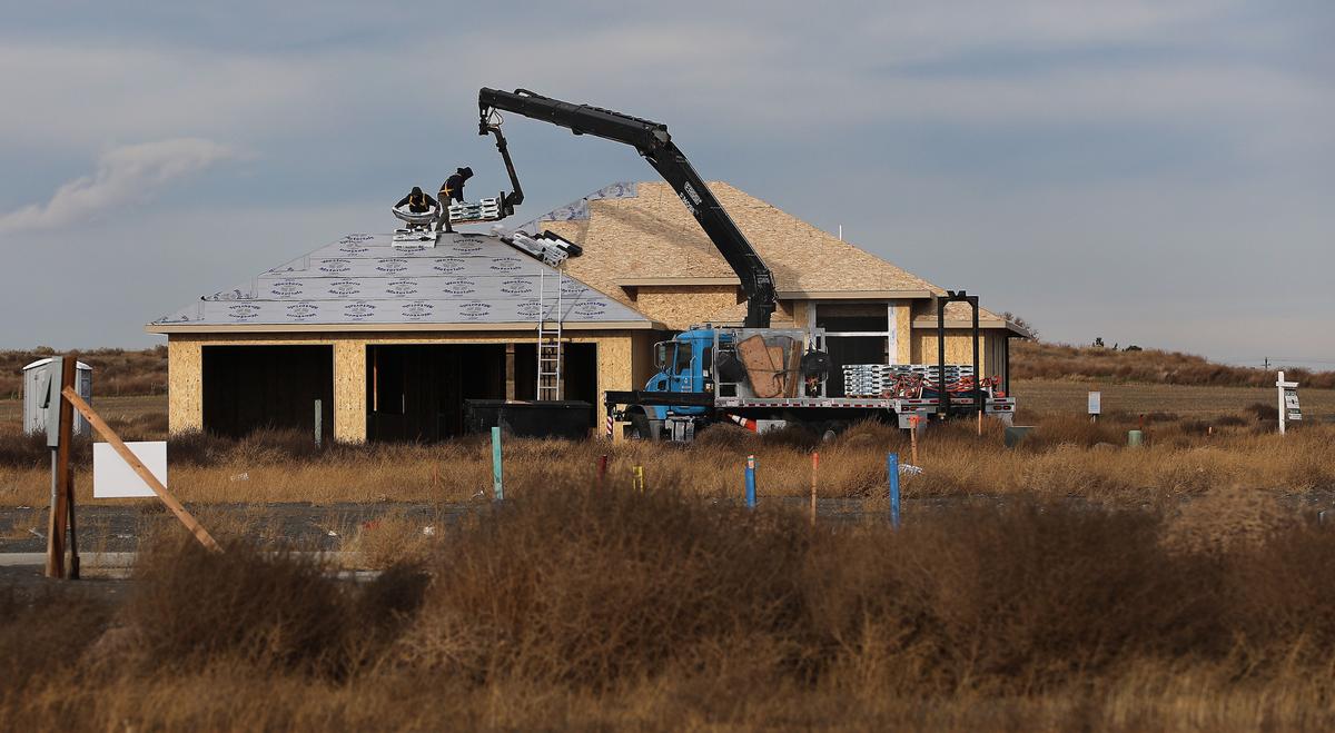 Construction workers unload shingles to the rooftop of a new home under construction on Nov. 18 in a new west Pasco housing development off Burns Road near Road 90.