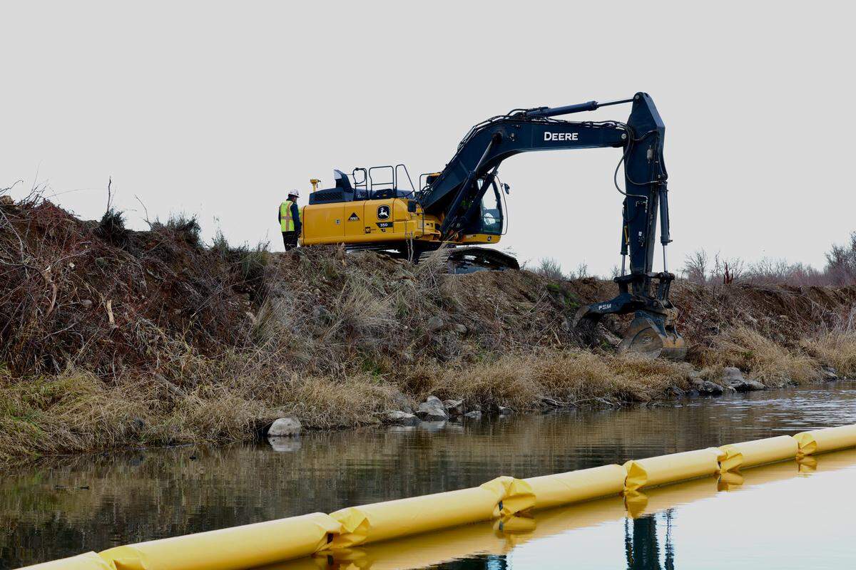Pipkin Inc., contractor for the $1.2 million Bateman Island causeway removal project in Richland, takes a bite out of the earthen dam linking the Columbia River shoreline to Bateman Island on Jan. 5, 2026.