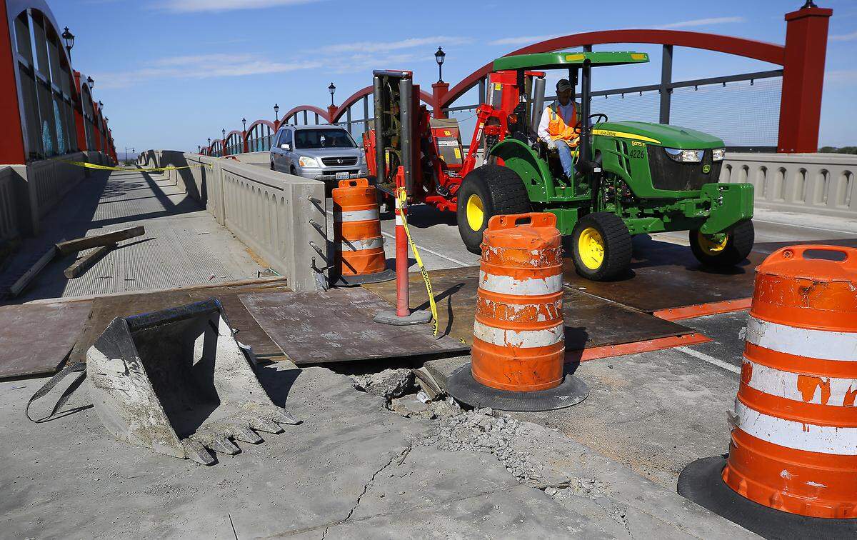 A tractor drives over steel plates covering the work at the transistion from pavement to concrete bridge decking on esast side the Lewis Street Overpass in Pasco.