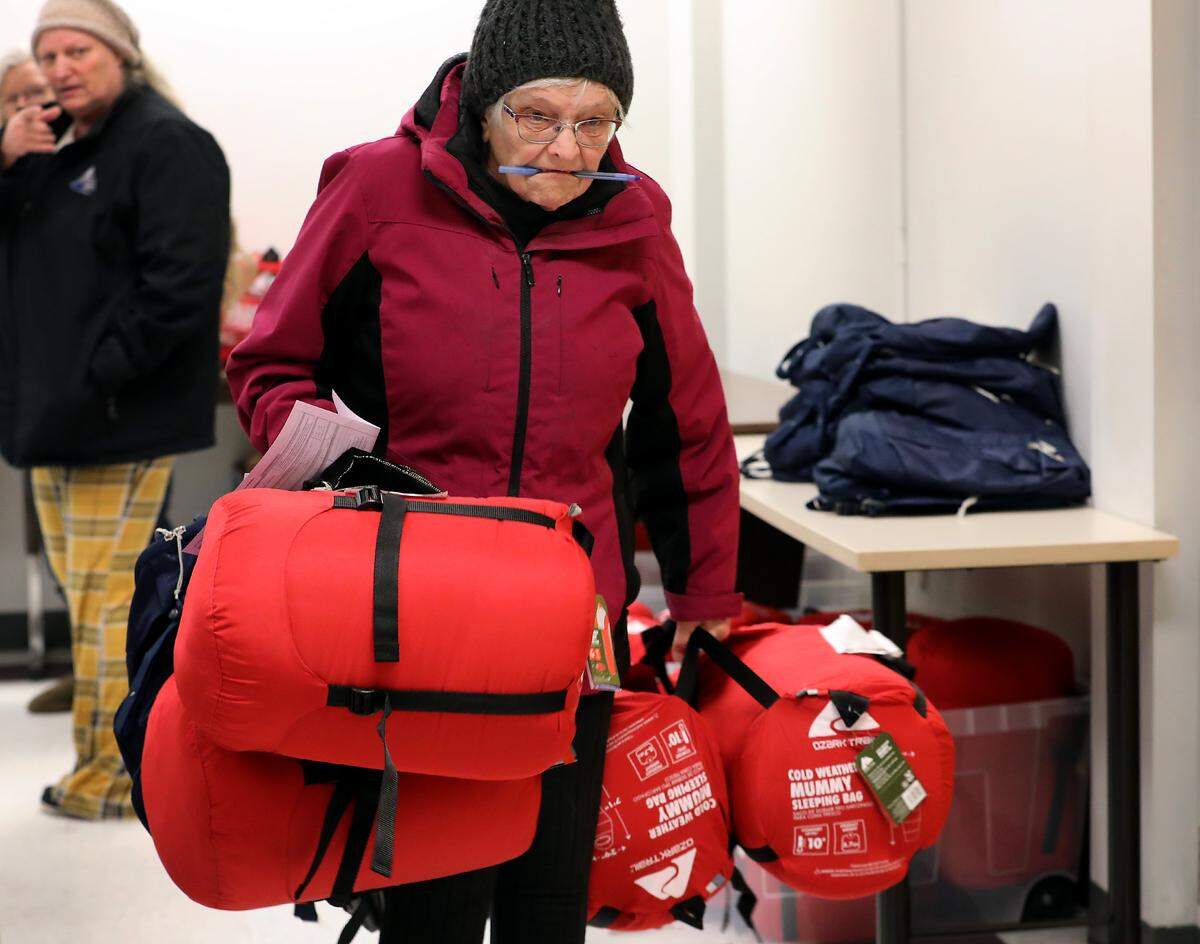 Volunteer Donna Kary carries a big load of sleeping bags and backpack care kits to a car while participating in the annual Point in Time homeless survey. 