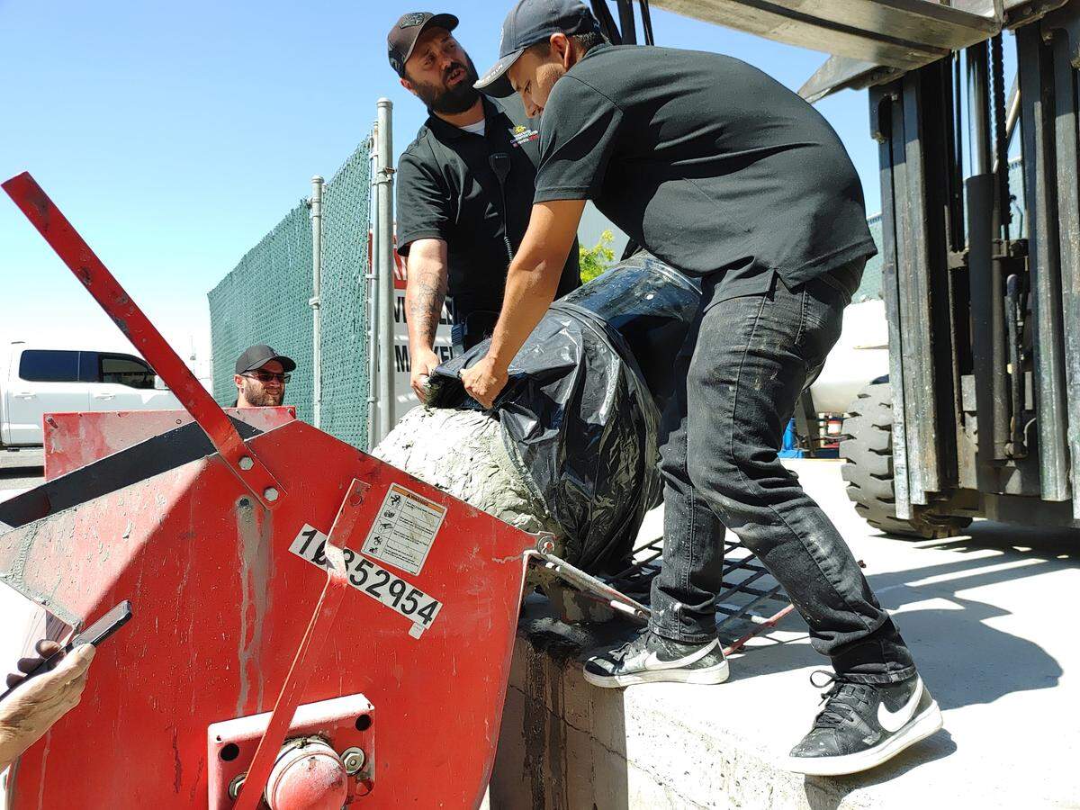 A crew at the Three Rivers Convention Center in Kennewick pours wet clay into a mixer to prepare it to be used to create horseshoe pits for the National Horseshoe Pitching Association’s 2024 World Tournament.
