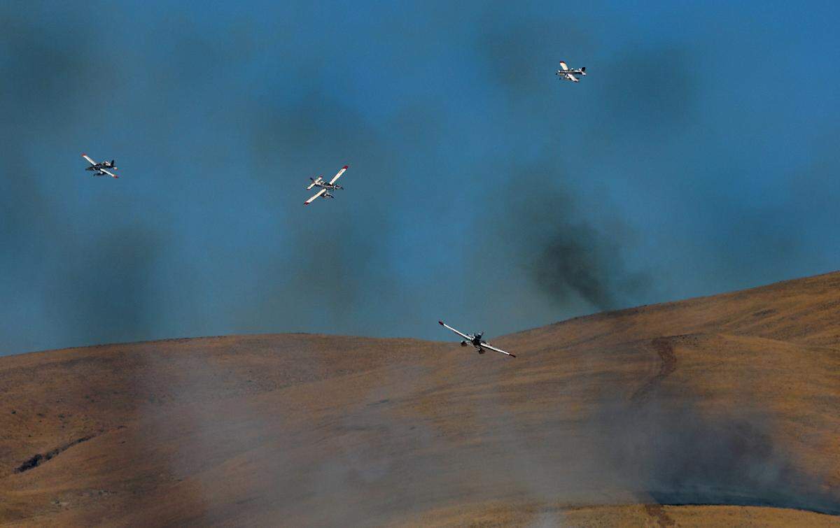 A group of firefighting aircraft line up in the sky preparing to drop their loads of water at a two-alarm wildfire that forced people from homes Monday afternoon just north of Benton City. There were no immediate details on the size or cause of the blaze.