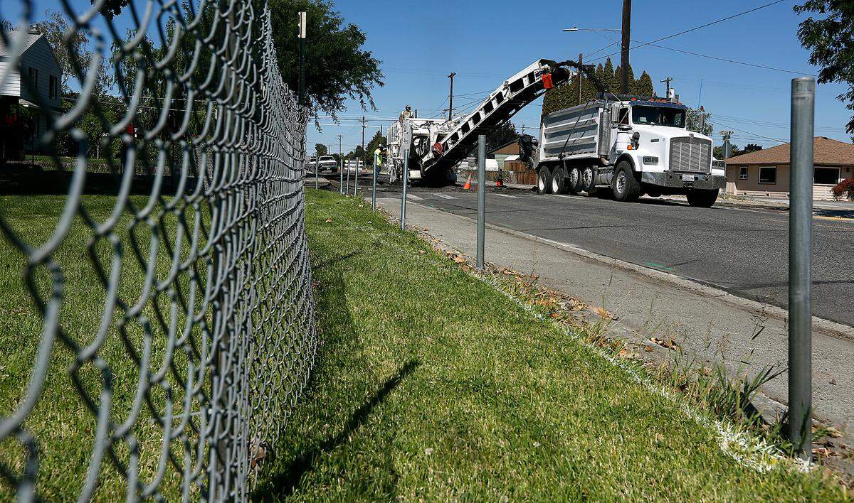 A pavement grinder removes a layer of asphalt as part of the project to construct a single lane mini roundabout in Richland.