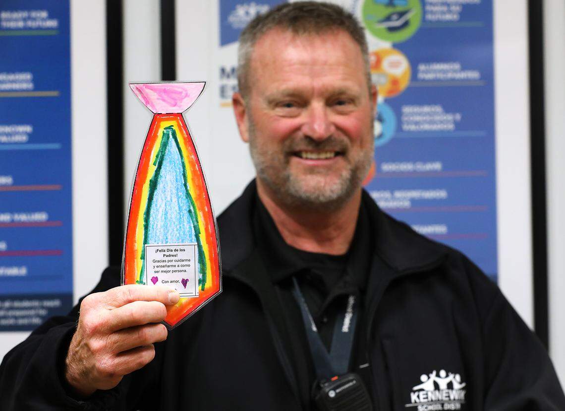 Scott Child, school safety and security manager for the Kennewick School District, holds up a laminated hand-decorated paper tie that an elementary student presented to him. 