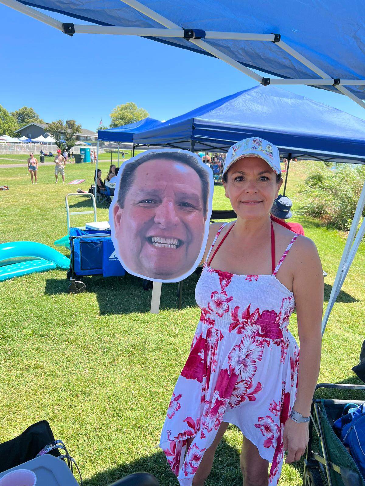 Angie Coleman poses along the shore at Tri-Cities Water Follies with a cardboard cutout photo of her friend Bob Duran, who died in September 2024.