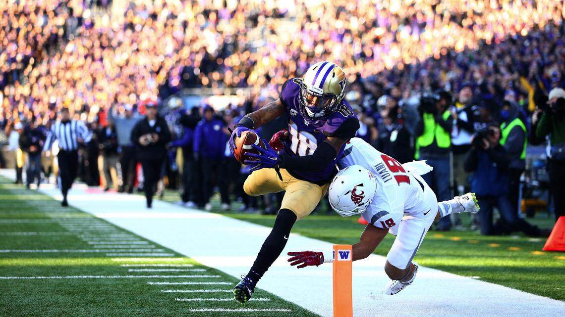 Washington’s Isaiah Renfro makes a leap for the endzone against the defense of Washington State’s Shalom Luani, right, during the first half in the 108th Apple Cup at Husky Stadium in Seattle in 2015.