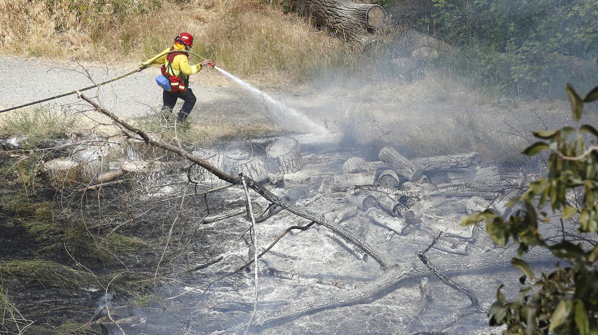 A firefighter douses smoldering spots Tuesday along the Spirit of America Trail in Zintel Canyon in Kennewick. The suspicious fire burned several acres and forced the park to close until it could be checked for safety risks.