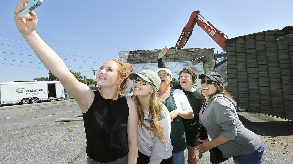 Hill's Restaurant employees Shayla Burruss, Maddy Bartleson, Teresa Edie, owner Nancy Galstad and Sonja Weber, from left, pose Tuesday in front of the fire damaged building on Vista Way in Kennewick. It was the first day of demolition before reconstruction begins.