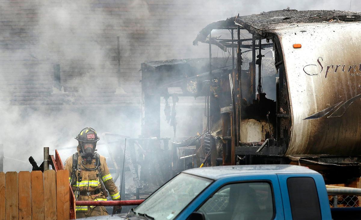 A firefighters walks past one of two trailers consumed by fire Thursday afternoon in the 3800 block of West Van Giesen Street in West Richland. Fire officials say one person was seriously injured in the blaze that was reported at about 12:30 p.m. Watch a video at: tricityherald.com/video
