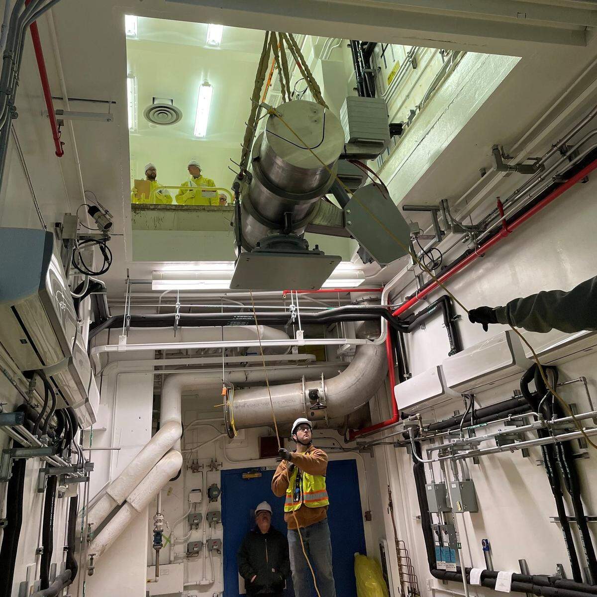 Workers are shown installing equipment in the Waste Encapsulation and Storage Facility in central Hanford to prepare to transfer radioactive cesium and strontium capsules to dry storage.