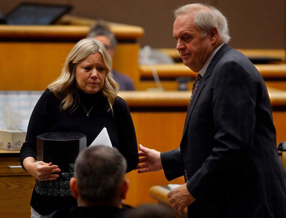 Then Benton County prosecutor Andy Miller helps widow Kris Mars as she carries an urn containing her husband’s ashes after making a statement at a 2022 resentencing hearing in Benton County Superior Court for convicted murderer Robert Suarez. 